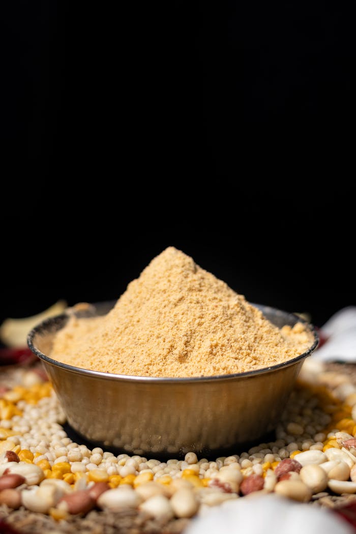 hero-img-02 Close-up of Indian spice masala in bowl with assorted grains, against black background, offering rich texture and color.