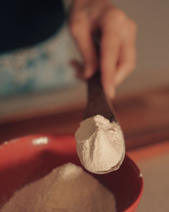 services-02 Close-up of flour being scooped into a red bowl, perfect for baking scenes.