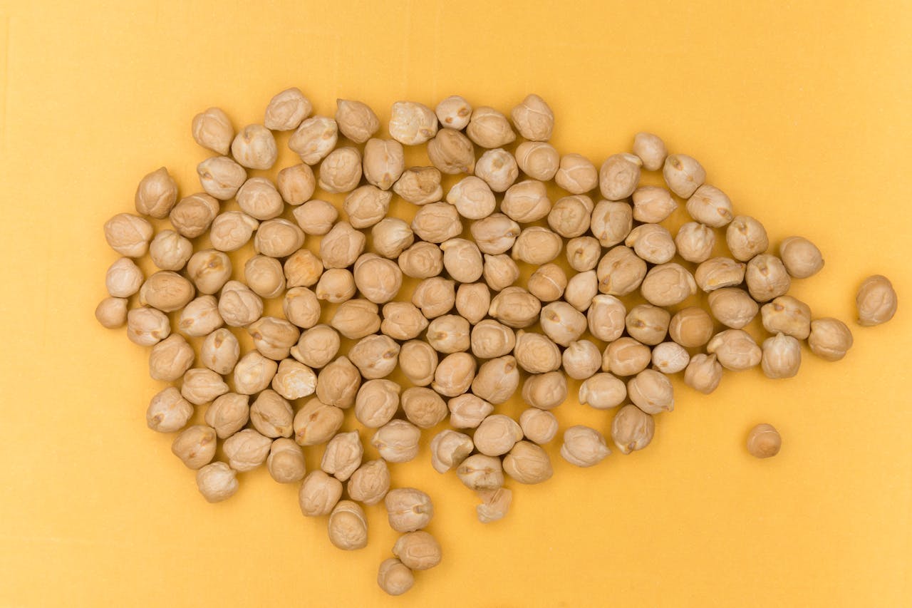 gallery-2 Close-up view of dried chickpeas on a vibrant yellow surface, emphasizing organic and healthy food.