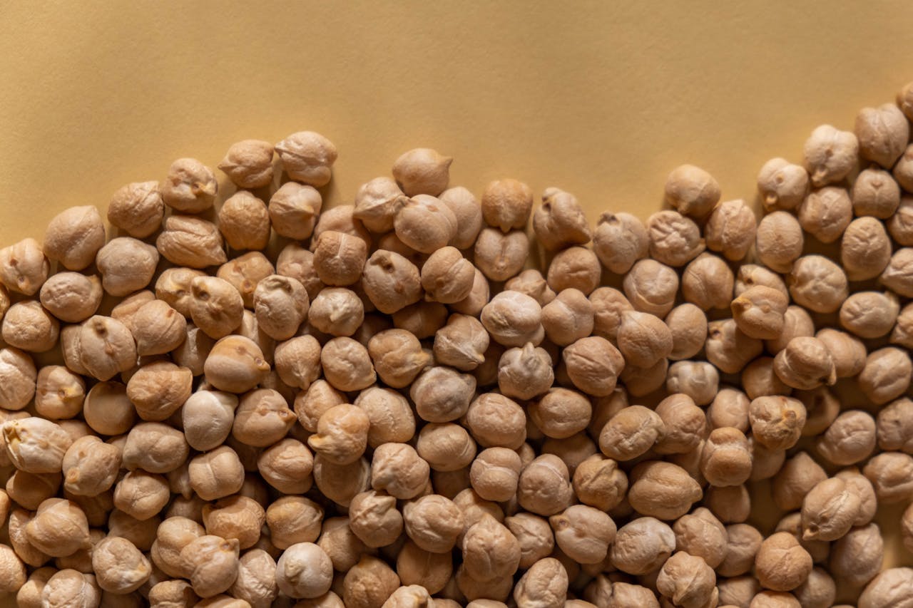 gallery-1 High-resolution close-up of organic dry chickpeas piled on a beige background, ideal for healthy food and ingredient themes.